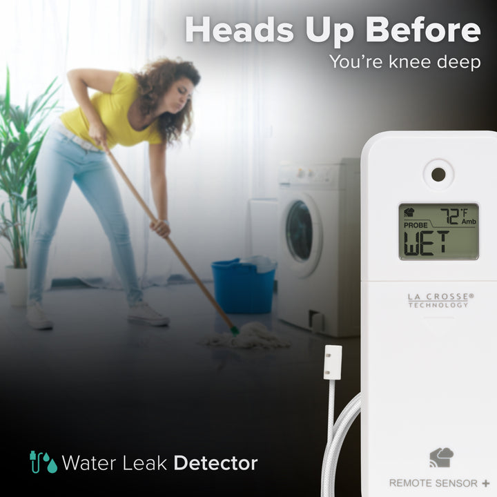 White alert and monitoring water leak area detection sensor with a braided cable in the foreground displaying an LCD screen reading wet and ambient temperature reading of 72 degrees Fahrenheit with a woman in a yellow t-shirt and jeans mopping up a floor in front of a front-load washing machine in the background