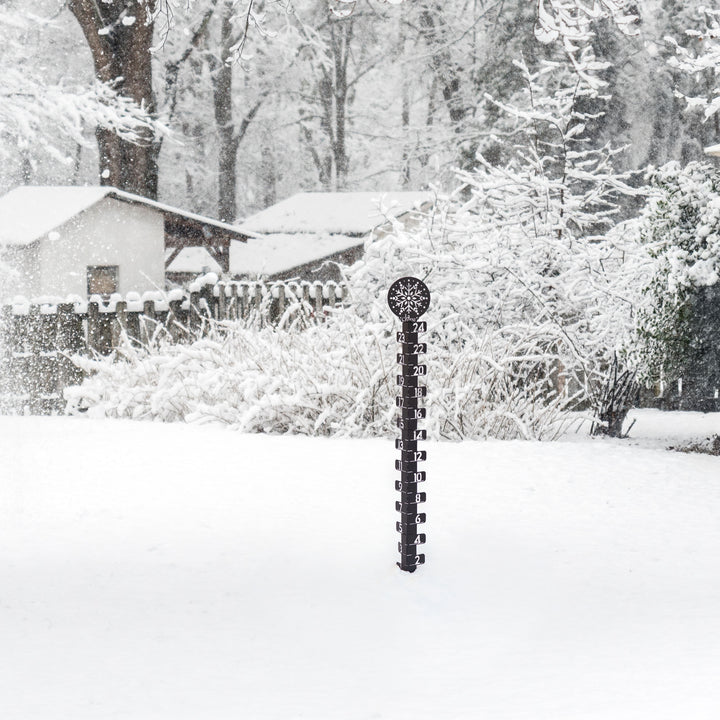 Lifstyle image of a snowy backyard with snow covered trrees, fencing, and house in the background with the 139-4686 Metal snowgague in the foreground