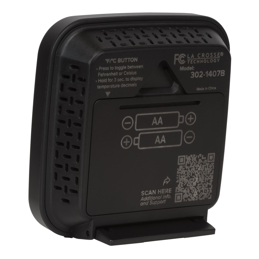 Back angled image of the 302-1407B Thermometer with Temperature and Humidity - Black. The image shows the hanging keyhole and the battery compartment with the fold down stand in use, there is a QR code for support and additional text to provide direction.