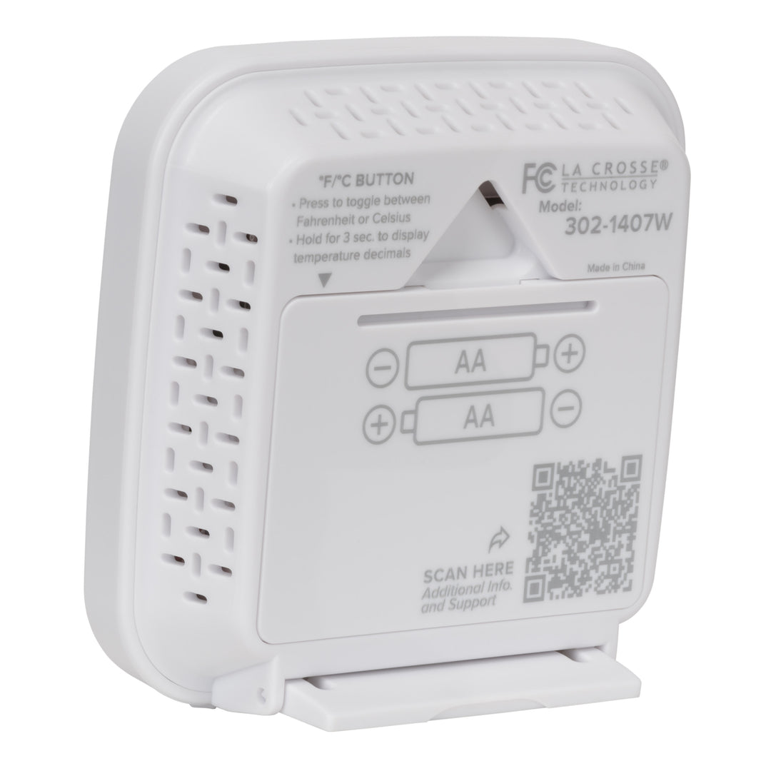 Back angled image of the 302-1407W Thermometer with Temperature and Humidity - White. The image shows the hanging keyhole and the battery compartment with the fold down stand in use, there is a QR code for support and additional text to provide direction.