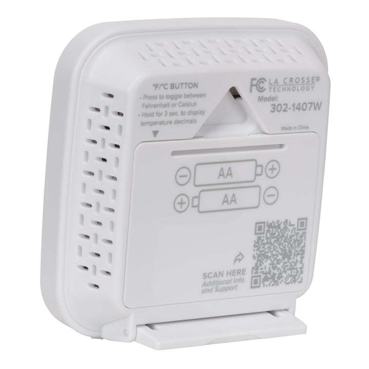 Back angled image of the 302-1407W Thermometer with Temperature and Humidity - White. The image shows the hanging keyhole and the battery compartment with the fold down stand in use, there is a QR code for support and additional text to provide direction.