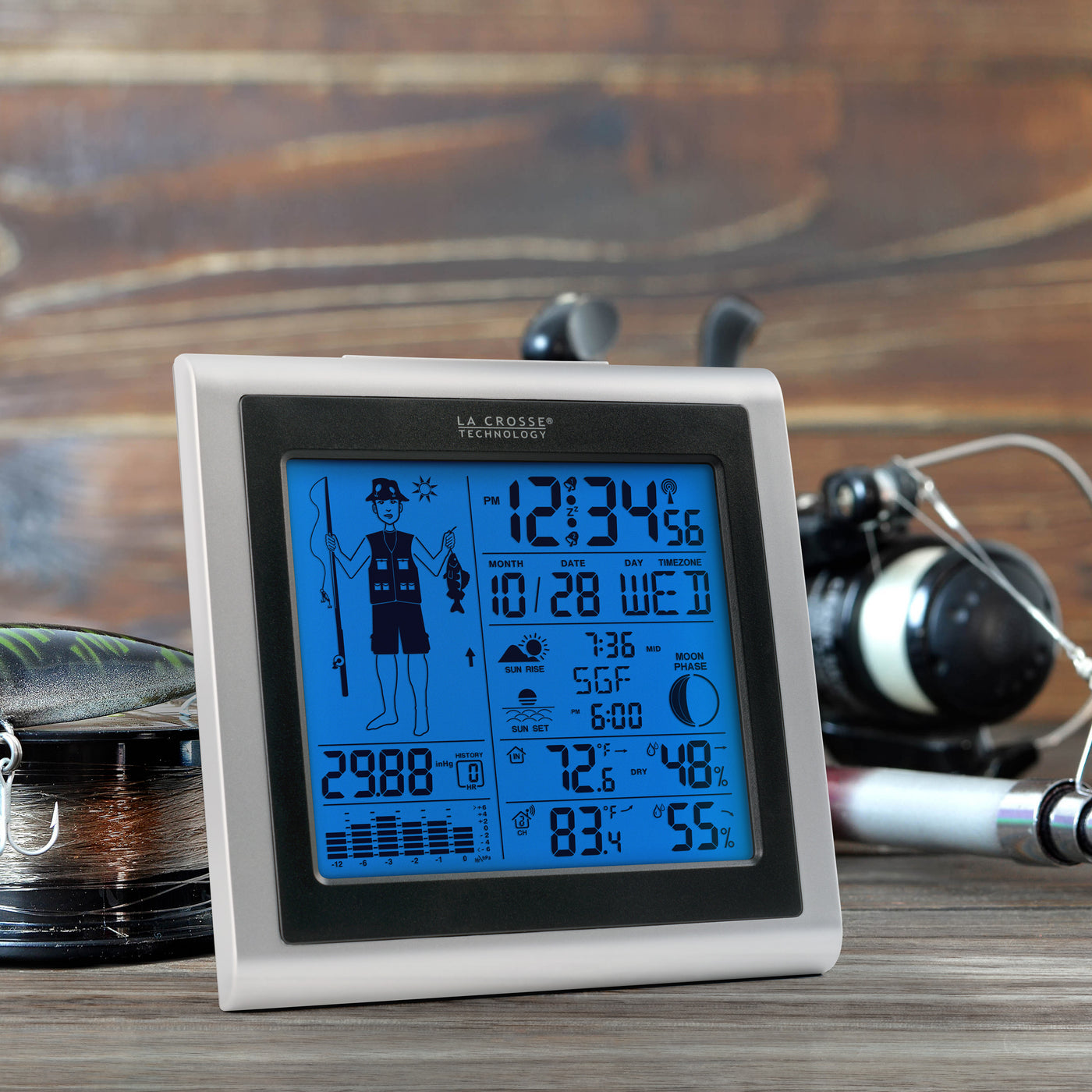 Fisherman icon weather station with blue backlight displayed with a fishing poll showing temp humidity sensor and readings including moon phase sunrise sunset barometric pressure graph in a silver and black case 