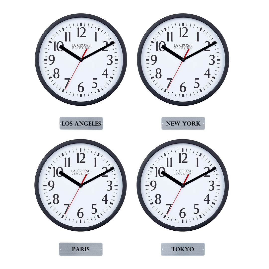 Head-on image of the 404-3020B-4TZ Four Pack 8-inch Basic Wall Clock with City Plaques showing all four clocks. The clocks feature black frames with white dials, black numbers, black hour and minute hands, and a red second hand. Beneath each clock is a small rectangular plaque labeling a city: “Los Angeles,” “New York,” “Paris,” and “Tokyo,” indicating different time zones.