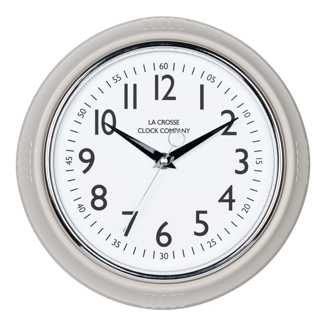 Head-on image of the 404-3024TP 9.5-inch Diner Clock – Taupe. The clock features a retro-style taupe frame with a white dial, chrome bezel, black numbers and minute markings, black metal hands, and a silver second hand.