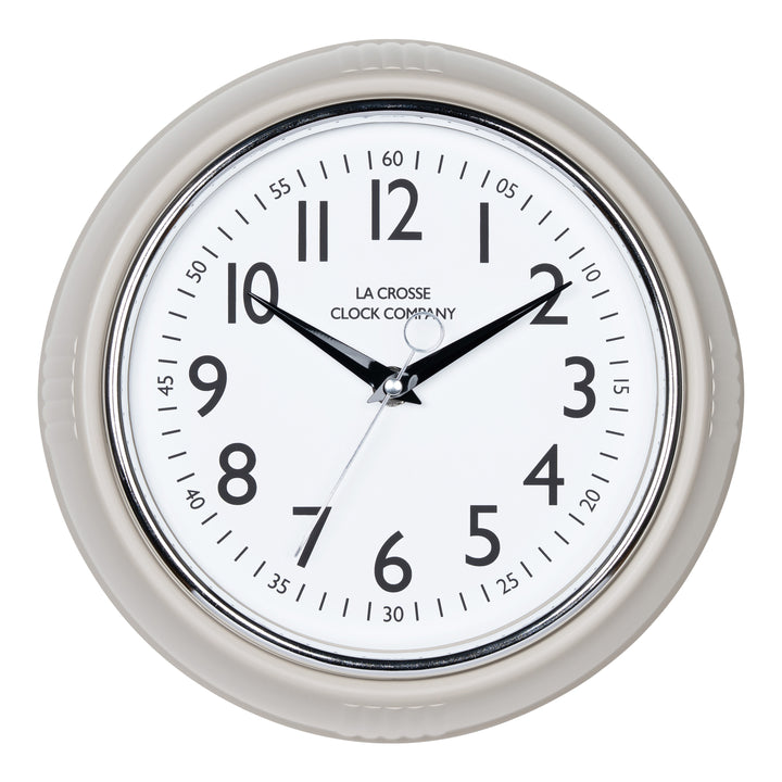 Head-on image of the 404-3024TP 9.5-inch Diner Clock – Taupe. The clock features a retro-style taupe frame with a white dial, chrome bezel, black numbers and minute markings, black metal hands, and a silver second hand.