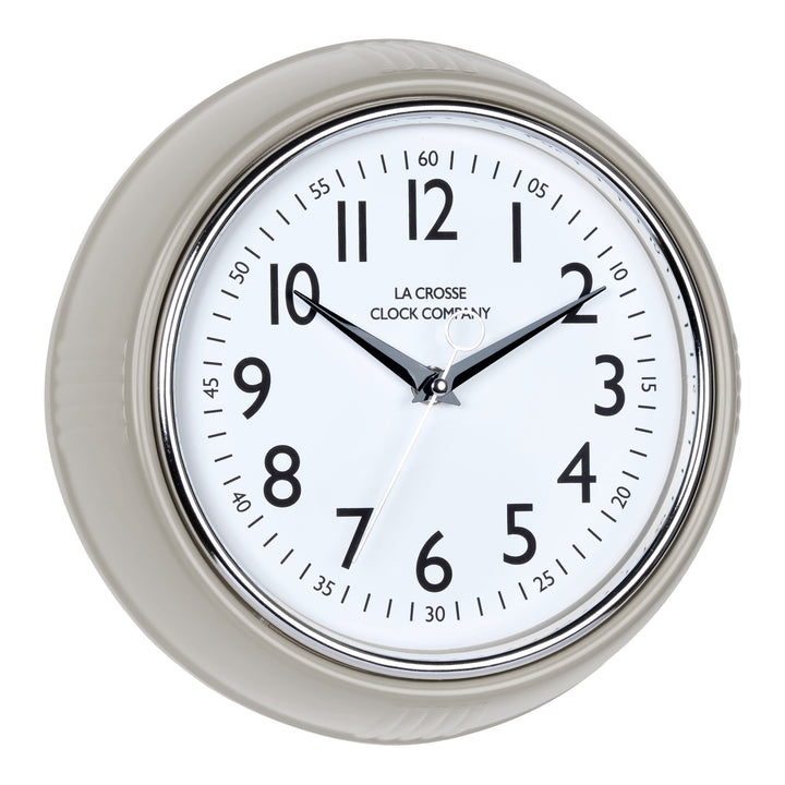 Right-facing image of the 404-3024TP 9.5-inch Diner Clock – Taupe. The clock features a retro-style taupe frame with a white dial, chrome bezel, black numbers and minute markings, black metal hands, and a silver second hand.