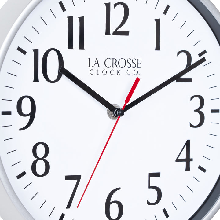 Close-up image of the dial of the 404-3025S 10-inch Basic Decor Wall Clock with a Silver frame, white dial with black numbers, hour, and minute hands, and a red second hand