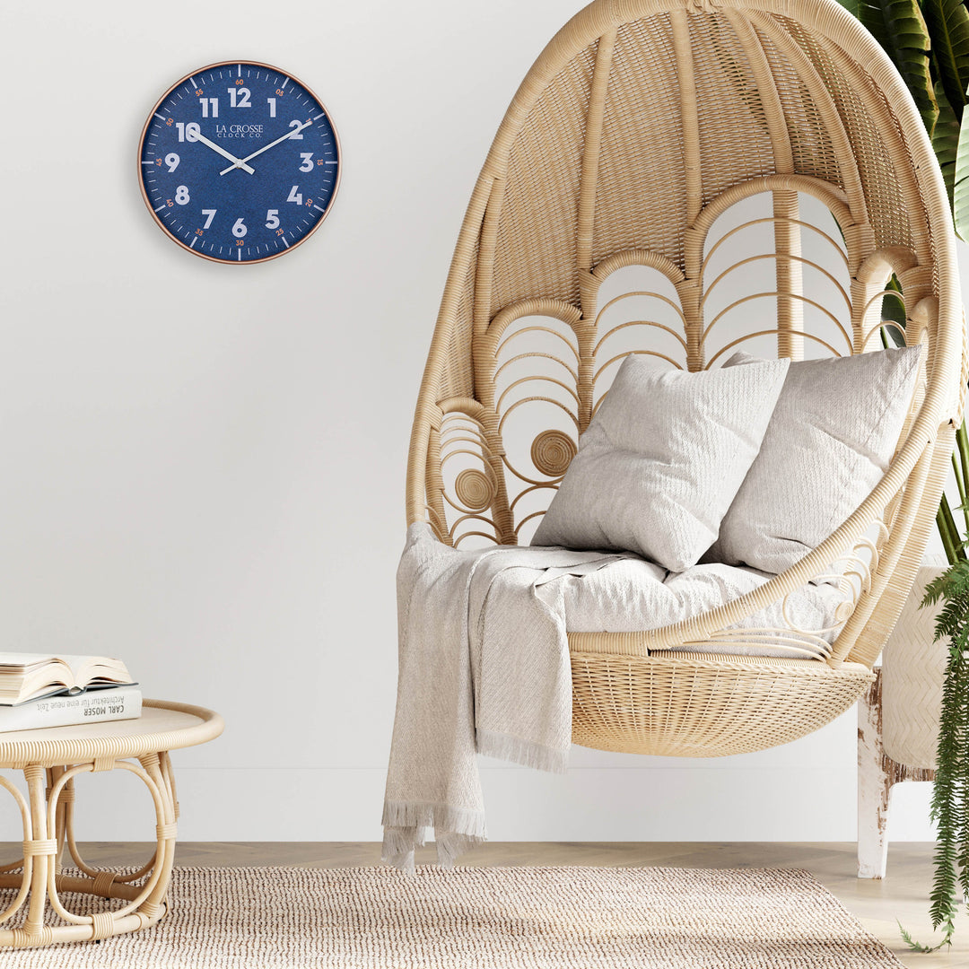 Lifestyle image of the 404-3027C Portside eleven inch navy blue wall clock with white numbers, orange time markings, and a copper case featuring white hour and minute hands in a nautical themed room