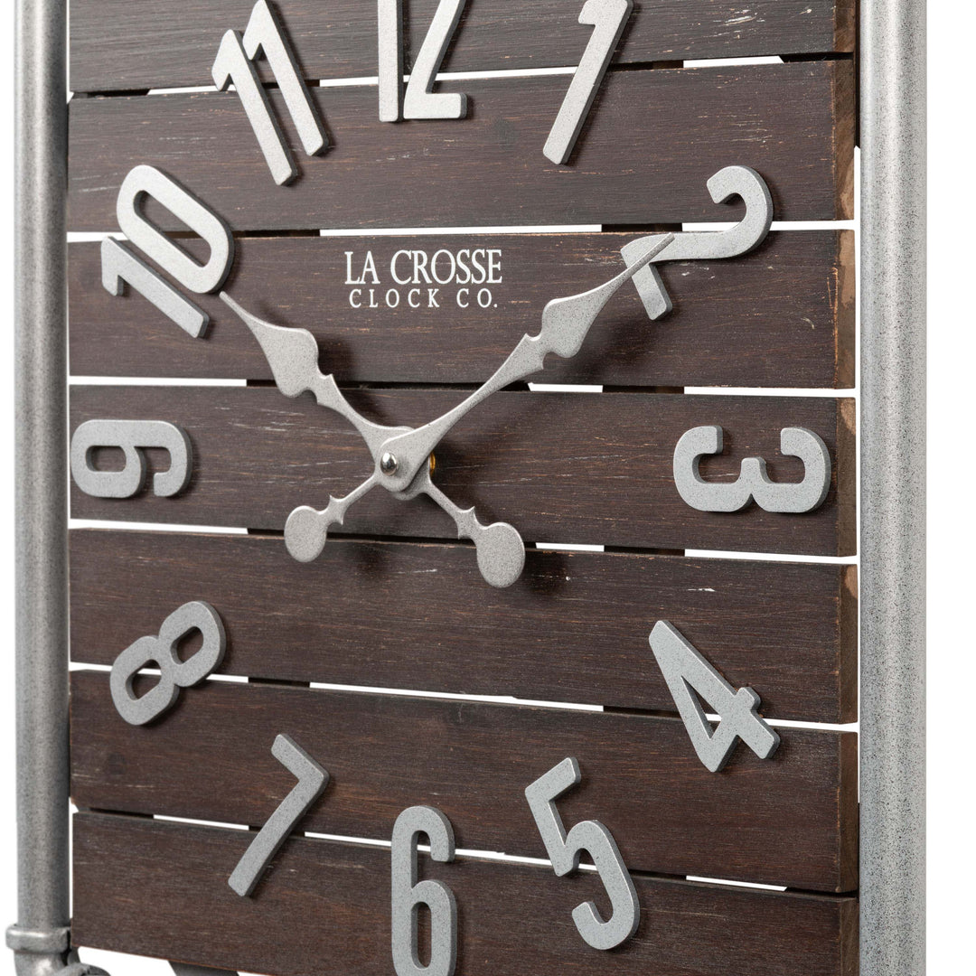 Close-up frame image of the 404-3412L 16-inch Foundry Metal &amp; Wood Wall Clock - Light. The clock features a square metal pipe frame, stained wood slats, and metal pewter finish accents.