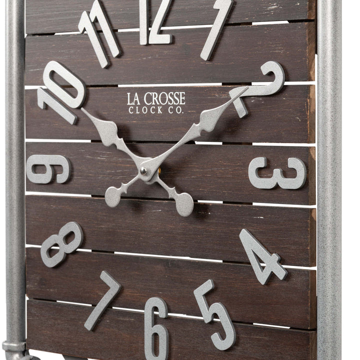 Close-up frame image of the 404-3412L 16-inch Foundry Metal &amp; Wood Wall Clock - Light. The clock features a square metal pipe frame, stained wood slats, and metal pewter finish accents.
