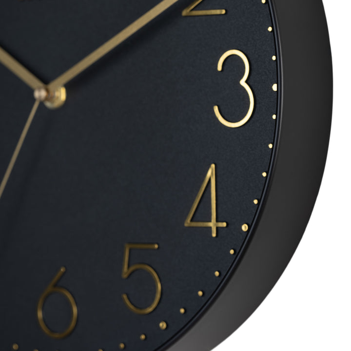 Close-up image highlighting the frame of the 404-3831B 12-inch Paxton Wall Clock - Black, with Silent Sweep, featuring a flush-mount black frame, a matching color dial, brass raised numbers, and brass-finished hour, minute, and second hands.