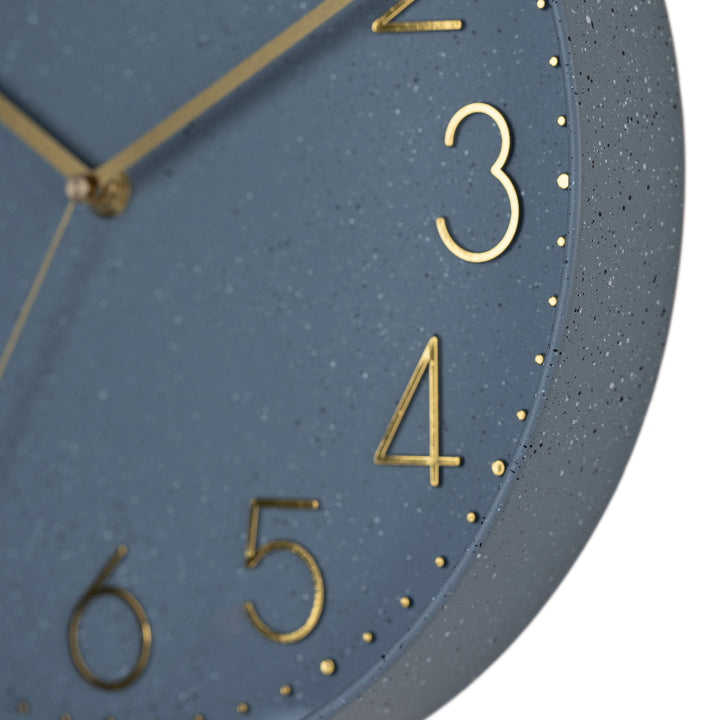 Close-up image highlighting the frame of the 404-3831SP 12-inch Paxton Wall Clock - Speckled, with Silent Sweep, featuring a flush-mount speckled blue frame, a matching color dial, brass raised numbers, and brass-finished hour, minute, and second hands.
