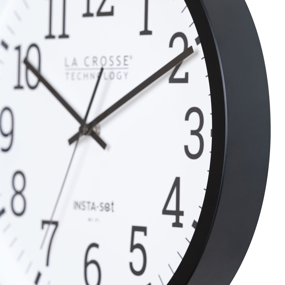 Close-up view of the frame of the 404-3836 Insta-Set Wi-Fi Wall Clock for iOS users. The clock features a black flush-mount frame, a white dial, black numbers, and black hands.