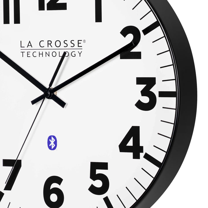 Close-up image of the frame of the 404-4536 14.2-inch Insta-Set Wall Clock with Bluetooth® Technology the clock features a white dial with bold black numbers and markings, a black flush-mount frame, and black hands