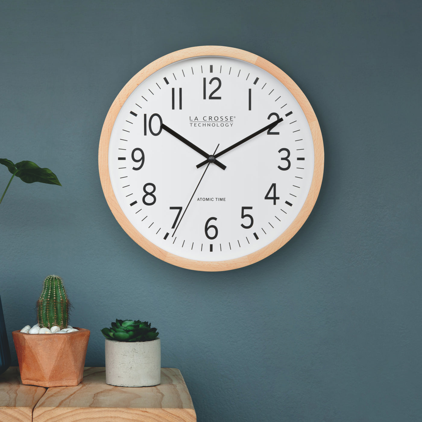 Wall clock with wooden frame on a blue wall, featuring 'La Crosse Technology' brand.
