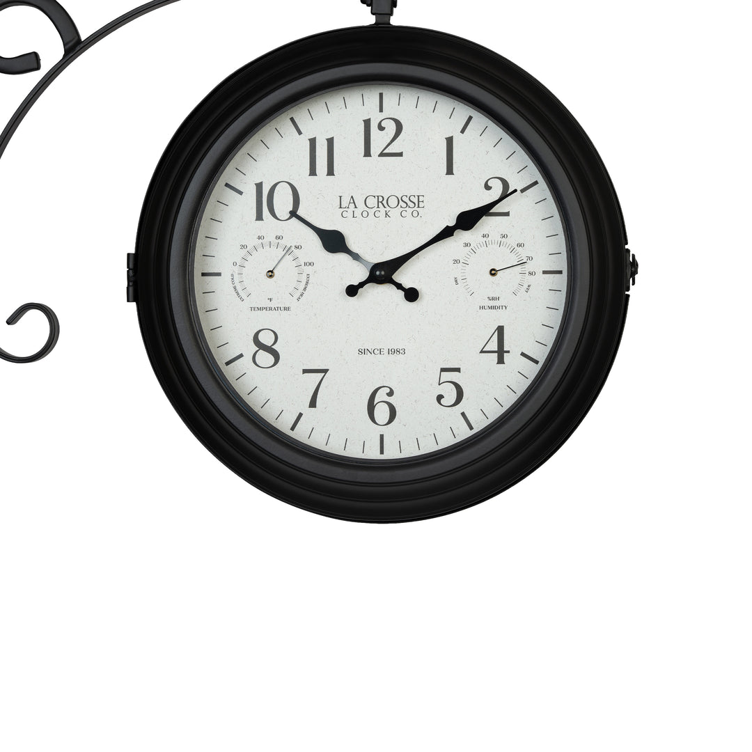 Clock close-up of the 425-34188 Outdoor Dual-Sided Metal Pedestal Clock. The clock features a temperature dial in a Fahrenheit scale, a humidity dial, decorative black metal hands, black numbers on a flecked white dial surrounded by a dark brown metal frame., with a 72-inch decorative scrollwork pedestal with a plant hanger.