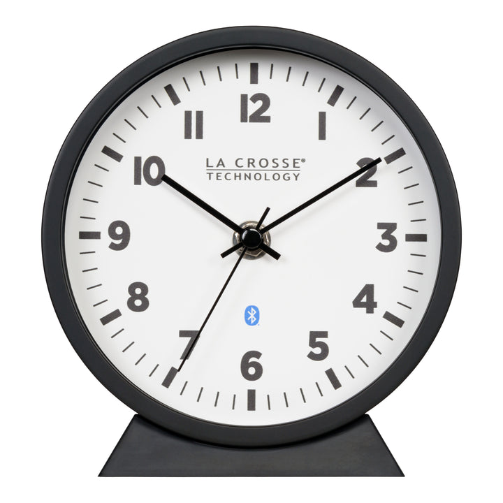 Head-on image of the 437-3816 Insta-Set Table/Wall Clock with Bluetooth® Technology featuring a white dial with bold black numerals, black metal hands, and a black frame with removable base for tabletop or wall hanging placement.