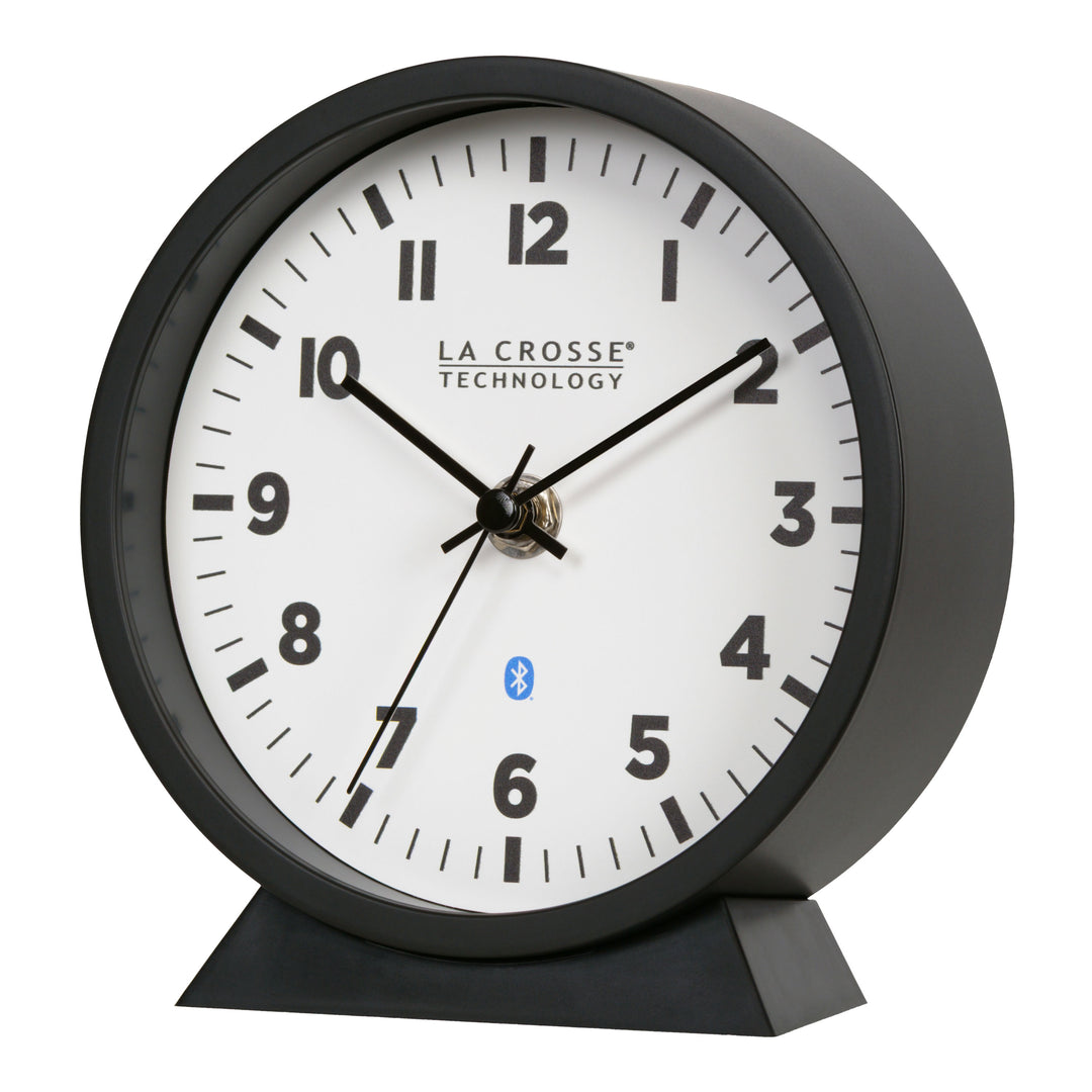 Left-facing image of the 437-3816 Insta-Set Table/Wall Clock with Bluetooth® Technology featuring a white dial with bold black numerals, black metal hands, and a black frame with removable base for tabletop or wall hanging placement.