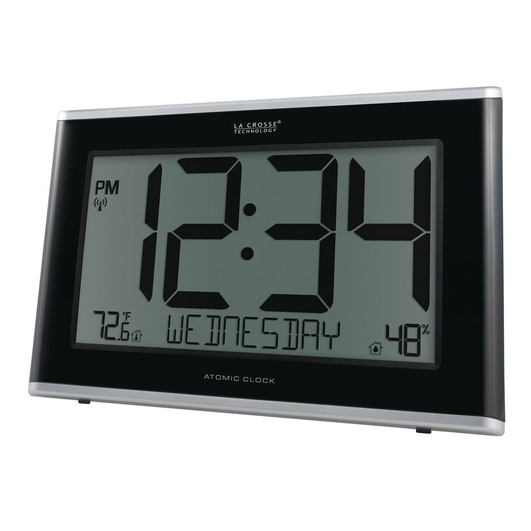 Angeld left-facing image of the 513-36908 Executive Atomic Digital Wall Clock with Temperature and Humidity features a black frame, a large LCD screen displaying 12:34 pm, Wednesday, indoor temperature, humidity, and signal icons.