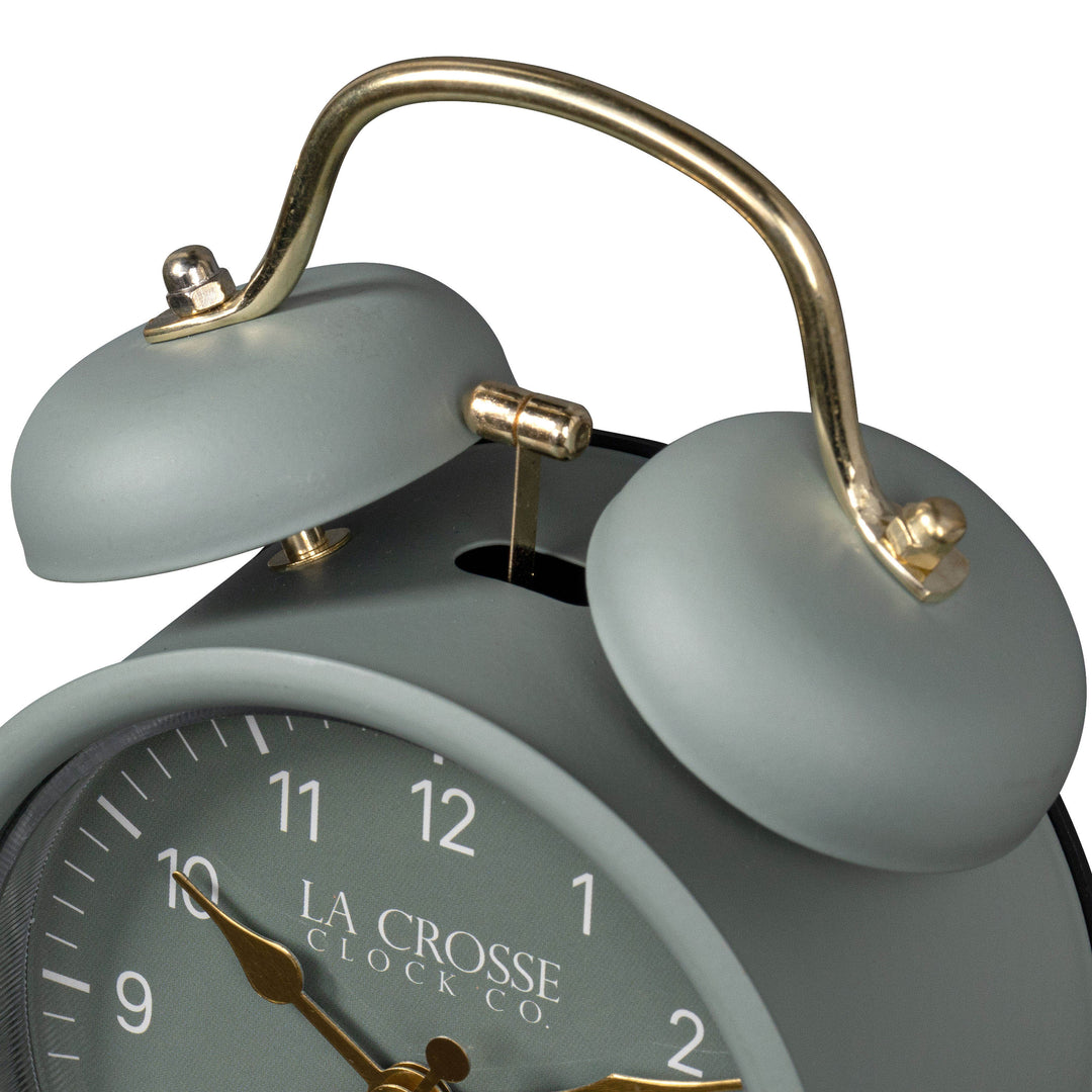 Close-up detail image of the 617-3314SG Metal Twin Bell Alarm Clock – Sage Green, showing the twin bell and hammer of the alarm clock. The clock features a Sage green dial with white numbers, gold hands and accents, in a sage green metal case.