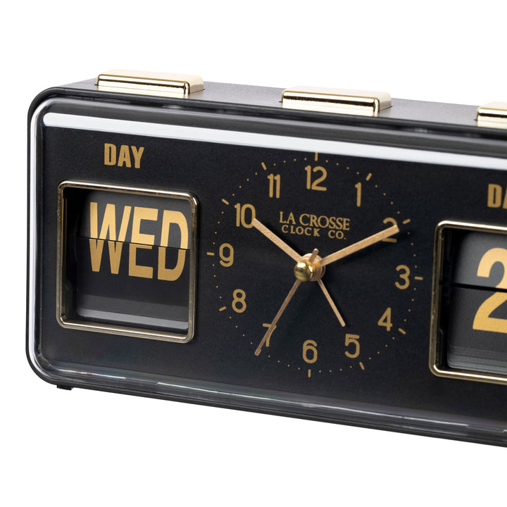 Angled close-up image of the 636-379B Daily Flip Tabletop Clock with Calendar – Black, featuring a retro design rectangular analog clock with brass numbers, hour, minute, and second hands, and a day and date calendar with manual flip cards with brass text.