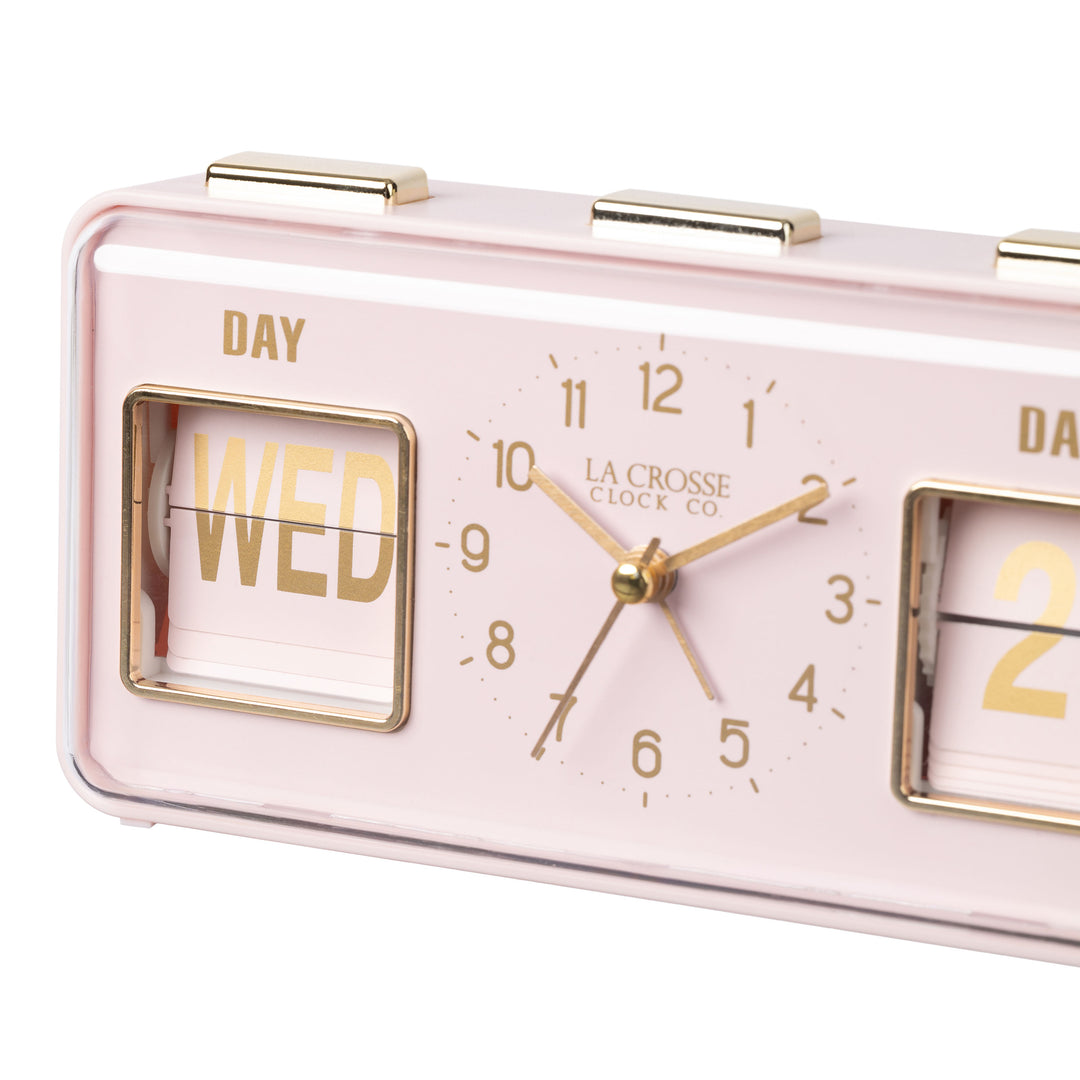 Angled close-up image of the 636-379P Daily Flip Tabletop Clock with Calendar – Pink Blush, featuring a retro design rectangular analog clock with brass numbers, hour, minute, and second hands, and a day and date calendar with manual flip cards with brass text.