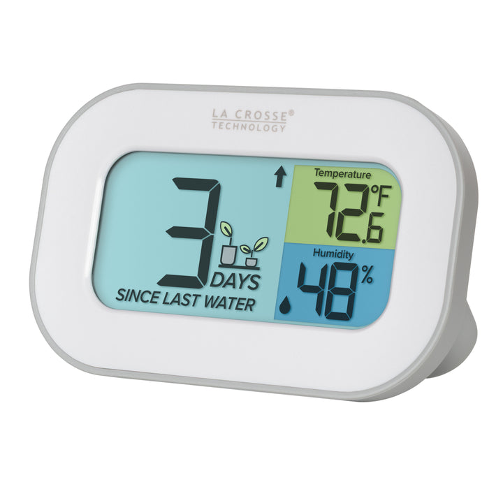 Left-facing image of the 919-147 Digital plant care timer with temperature and humidity. The timer is battery-operated and features a white and gray oval case with a screen sectioned into three colors. The turquoise blue section indicates how many days since the last watering with a graphic of plants and an up arrow, the yellow section lists the temperature at 72.6 degrees Fahrenheit, and the dark blue section lists the humidity level at 48 percent with a water drop icon.